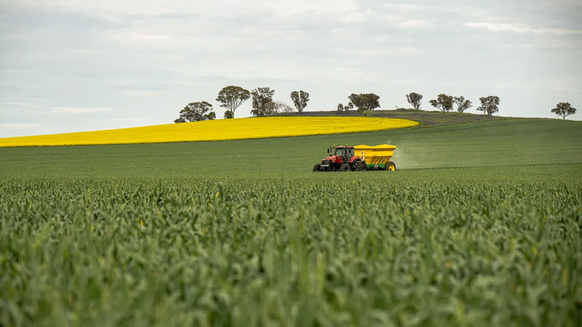 tractor fertilizing a crop field with a spreader