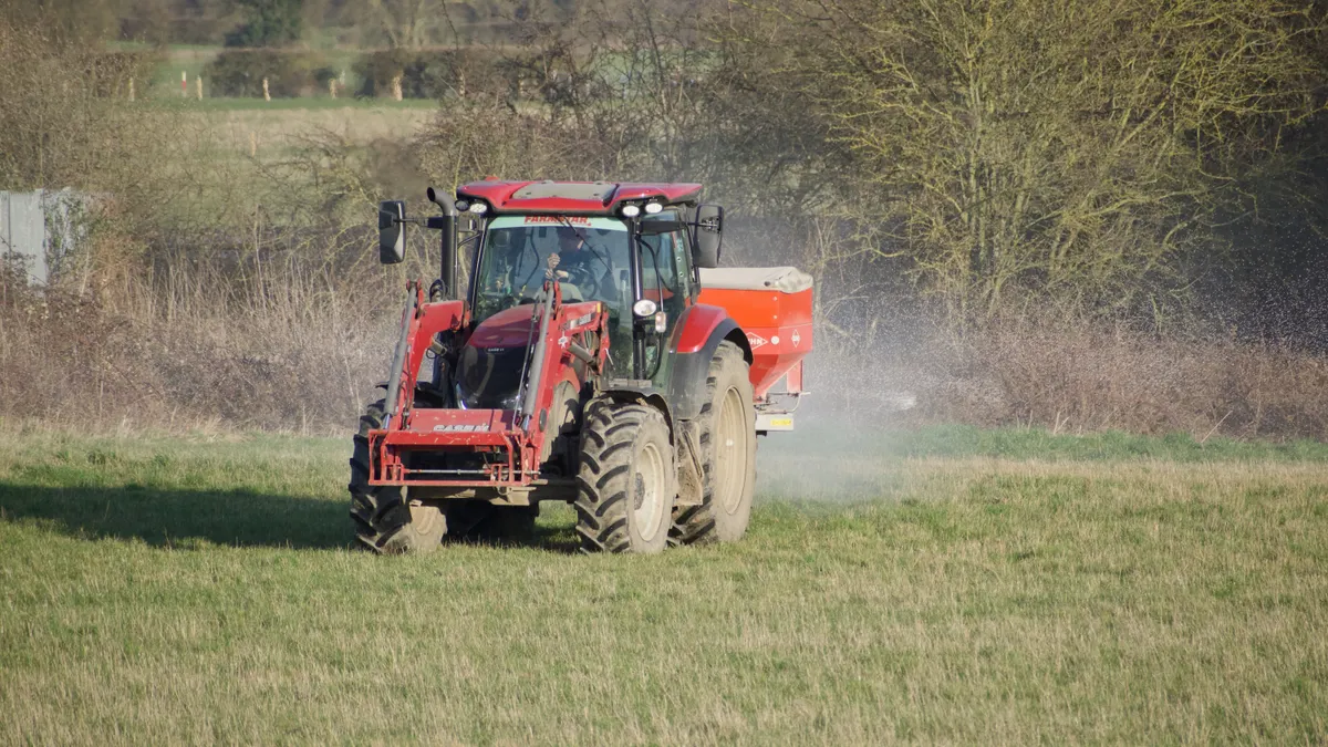 tractor spraying or spreading on grassy land