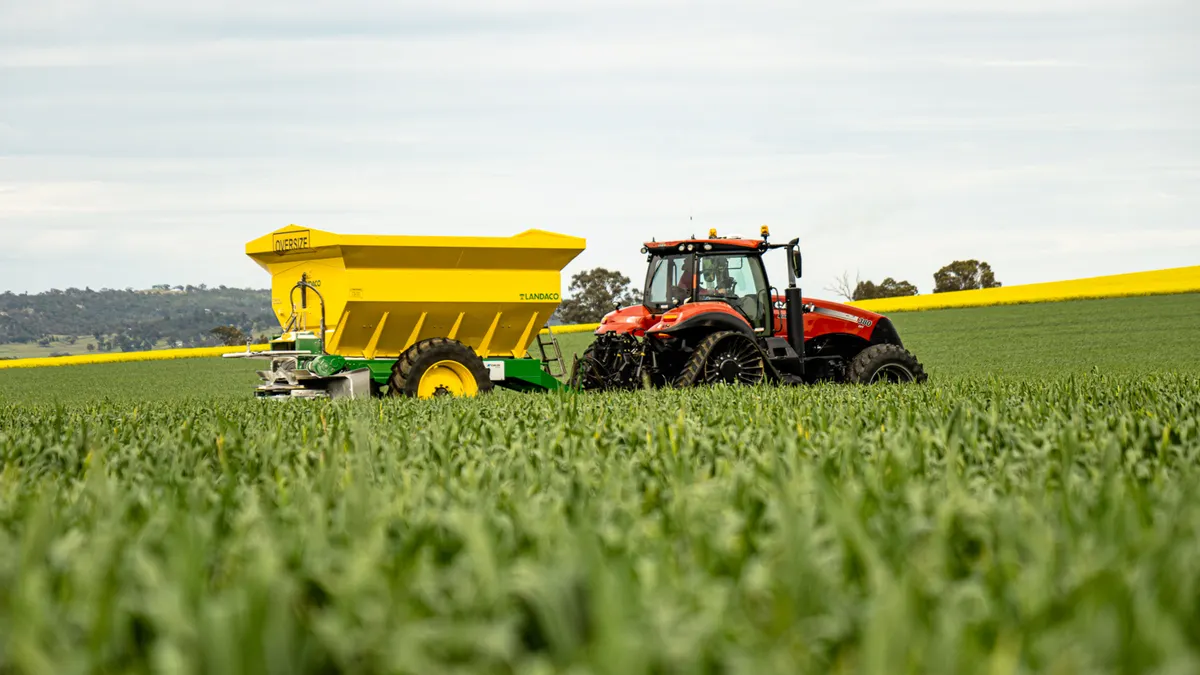 How to fertilize a lawn without burning it tractor spreading fertilizer across a green field